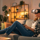 Eine Frau sitzt entspannt auf dem Sofa in einem stilvoll eingerichteten Wohnzimmer und nutzt eine VR-Brille für ein immersives Einkaufserlebnis. Virtuelle Realität als ein wichtiger E-Commerce-Trend 2025 ermöglicht es, Produkte vor dem Kauf interaktiv zu erleben